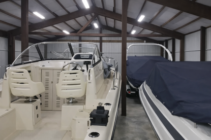 Clean indoor boat storage warehouse in Bellevue, WA showing a Grady-White boat parked inside with concrete floors, wood beams, and bright overhead lighting.